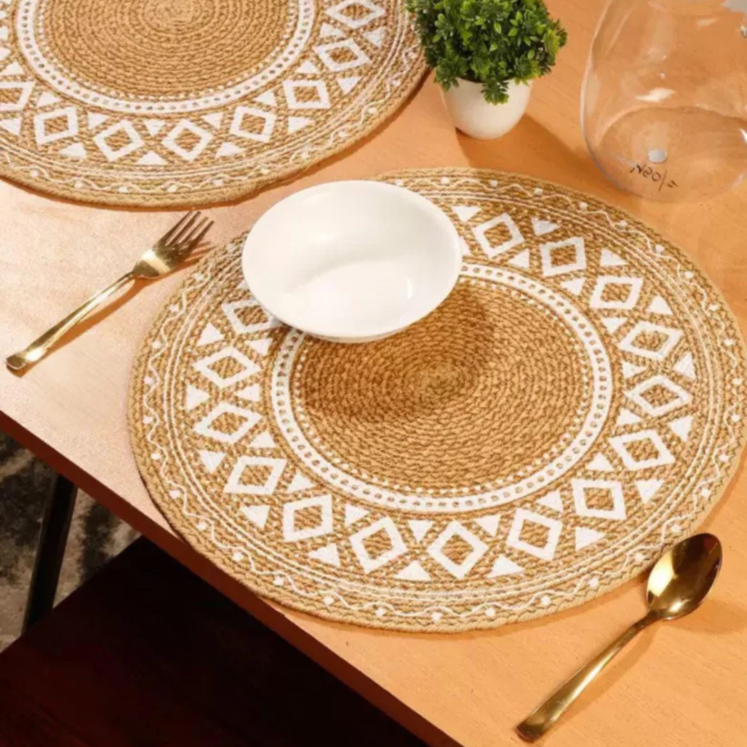 Round cotton table mat with white geometric patterns, featuring a white bowl and gold cutlery on a wooden table.
