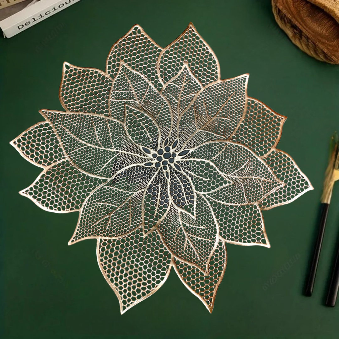 White bowl and small dish with spoon on a lace-like, leaf-shaped gold placemat over a green surface.