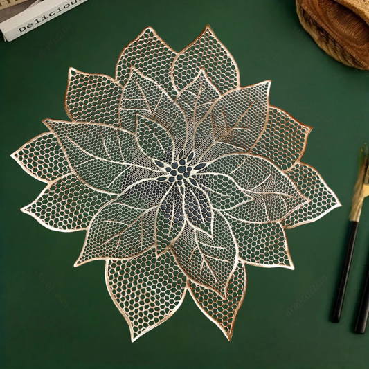 White bowl and small dish with spoon on a lace-like, leaf-shaped gold placemat over a green surface.
