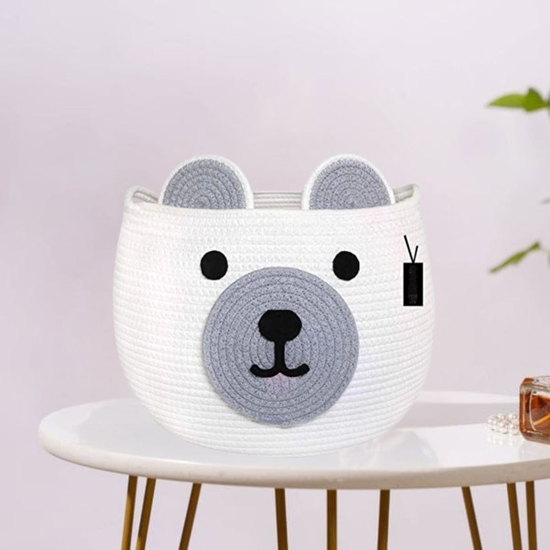This is a cute white basket designed to look like a bear’s face, with gray ears and snout details. It's perfect for kids' rooms, toy storage, or as a playful decor piece!