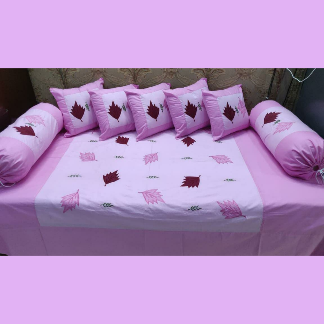 Designer-cotton-diwan-set-rose-pink-embroidered-with-five-cushion-cover-and-two-booster-cover-placed-on-bedsheet-in-organized-manner