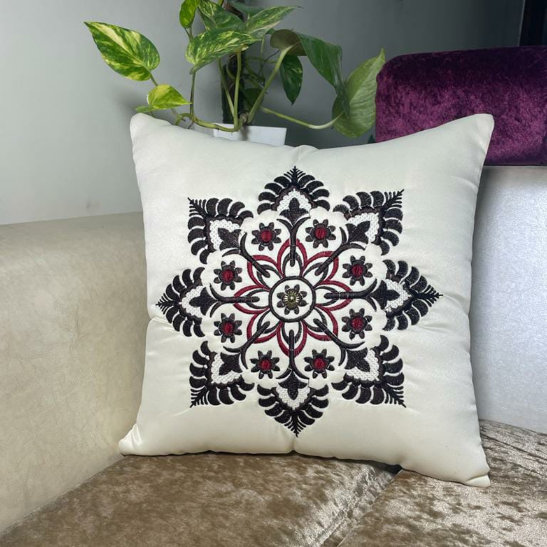 floral embroidered cushion cover in white color of satin fabric placed on cream colour sofa