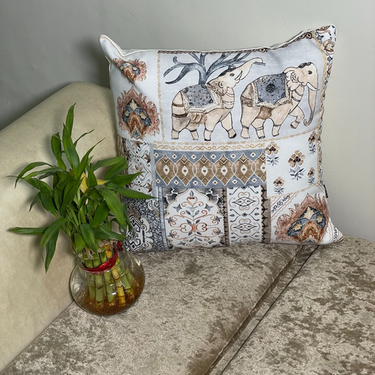 elephant printed cushion cover in brown color of 100% cotton fabric with madhubani print lies in the corner of sofa with a plant