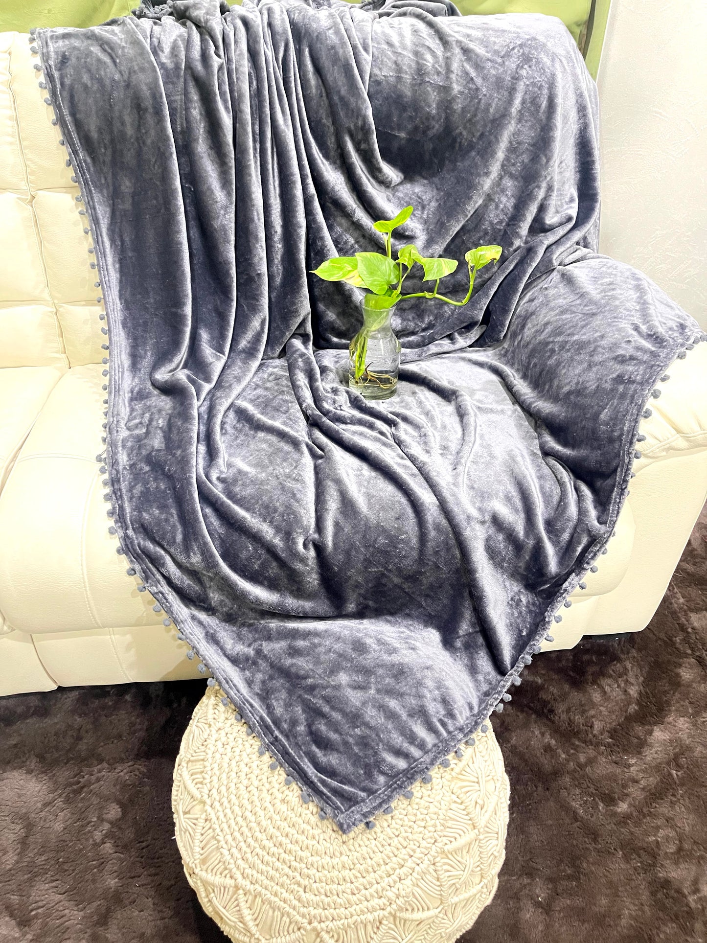 loomsmith-solid-AC-blanket-double-bed-solid-flannel-with-pom-pom-all-four-sides-in-ash-grey-color-placed-on-sofa-ac-use-vibrant-color