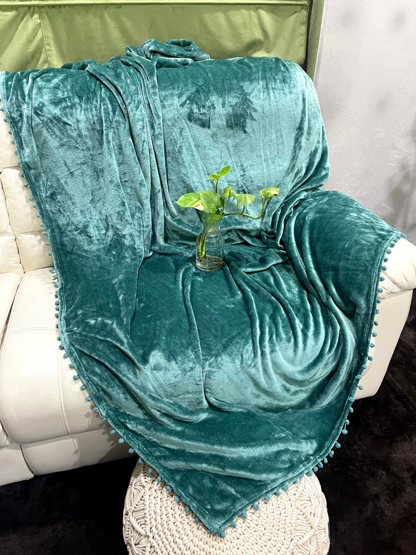 loomsmith-solid-AC-blanket-double-bed-solid-flannel-with-pom-pom-all-four-sides-in-green-color-placed-on-sofa-ac-use-vibrant-color