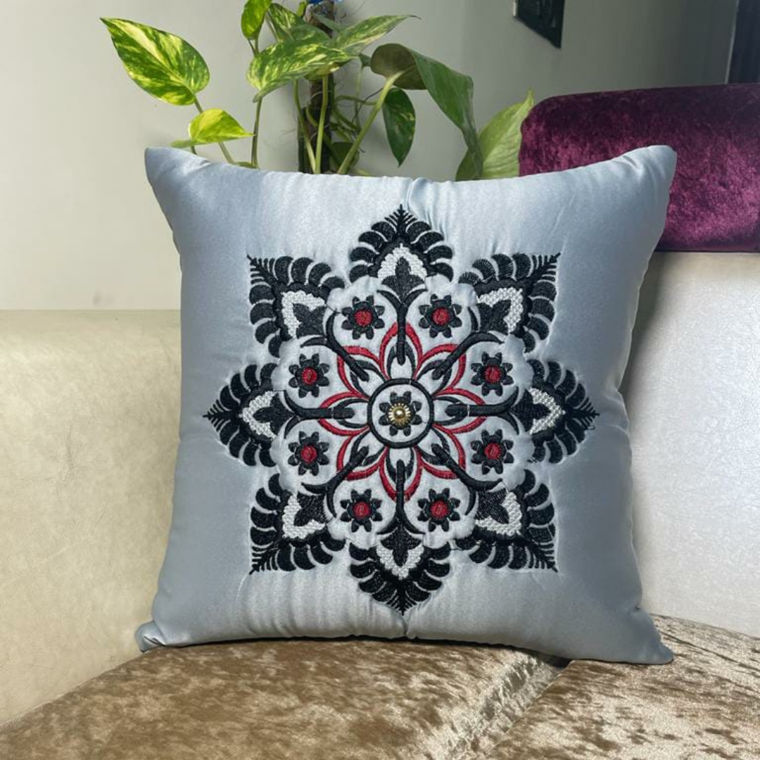 floral embroidered cushion cover in grey color of satin fabric placed on cream colour sofa 