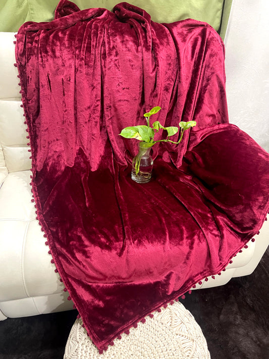 loomsmith-solid-AC-blanket-double-bed-solid-flannel-with-pom-pom-all-four-sides-in-maroon-color-placed-on-sofa-ac-use-vibrant-color