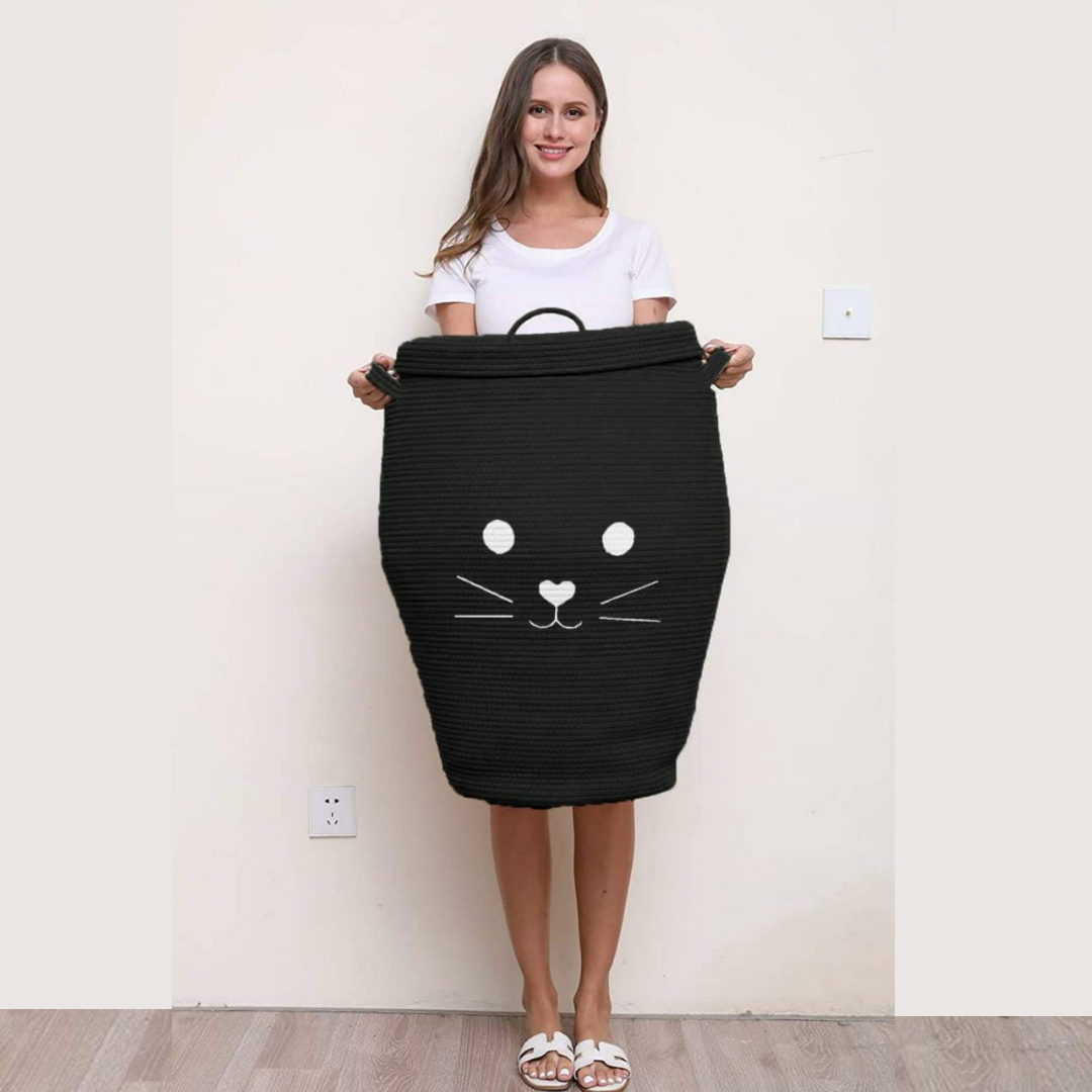 Cat-face-storage-basket-with-lid-in-Black-coloroman-carrying-it-with-strong-handles-in-background