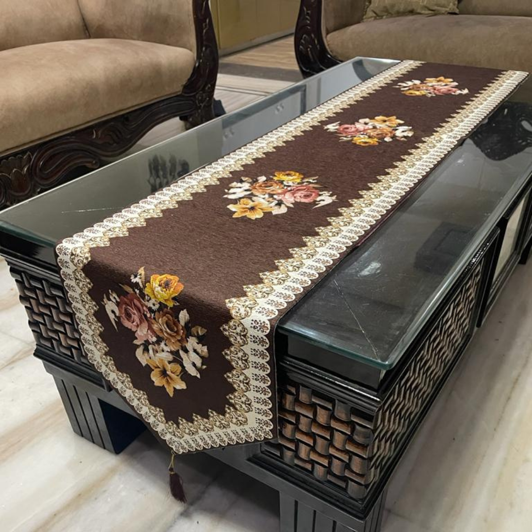 floral printed dining table runner in brown color design with a tassel on both ends borders printed placed on glass wooden table Side view