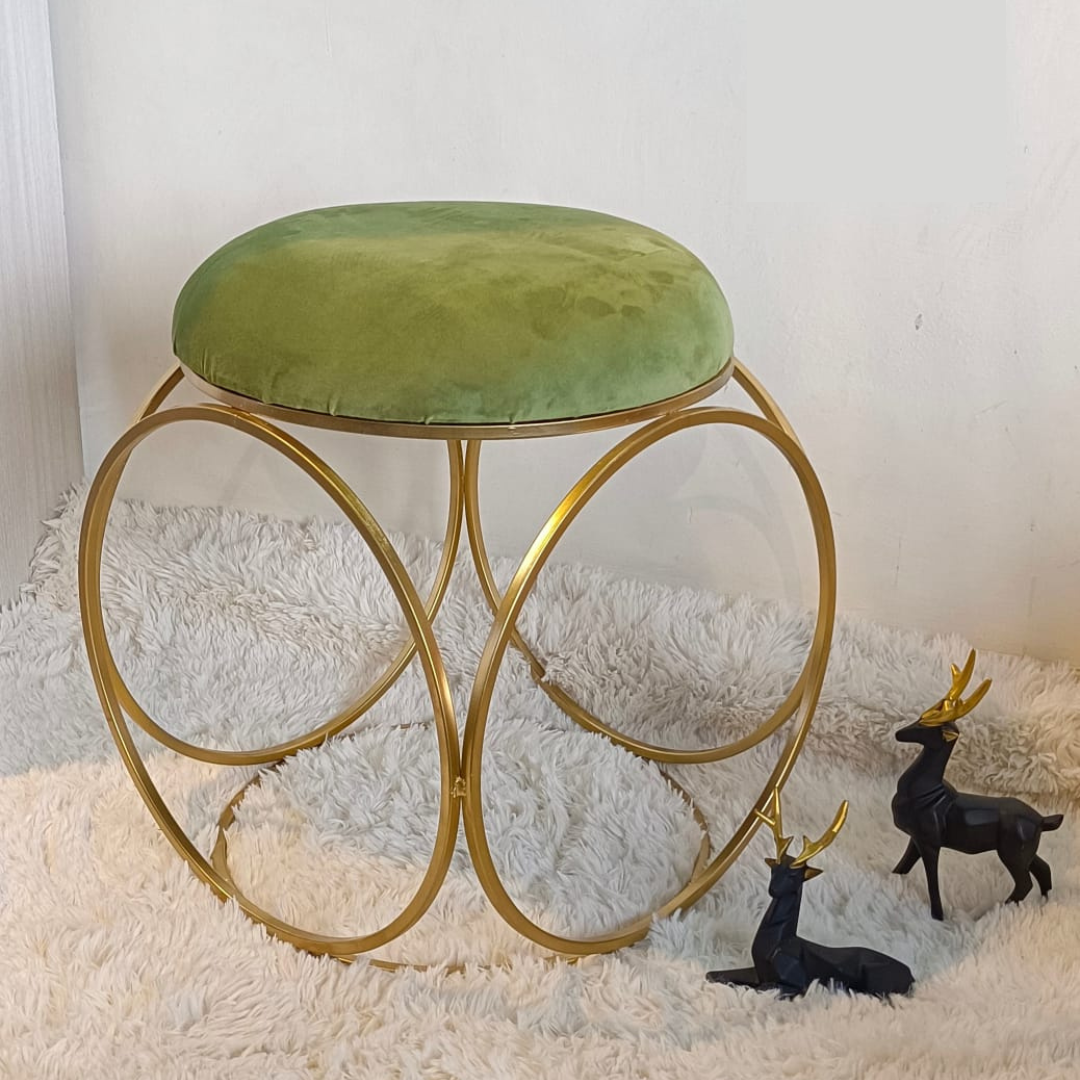 round design gold metal stool with puffy top in green color placed on soft rug