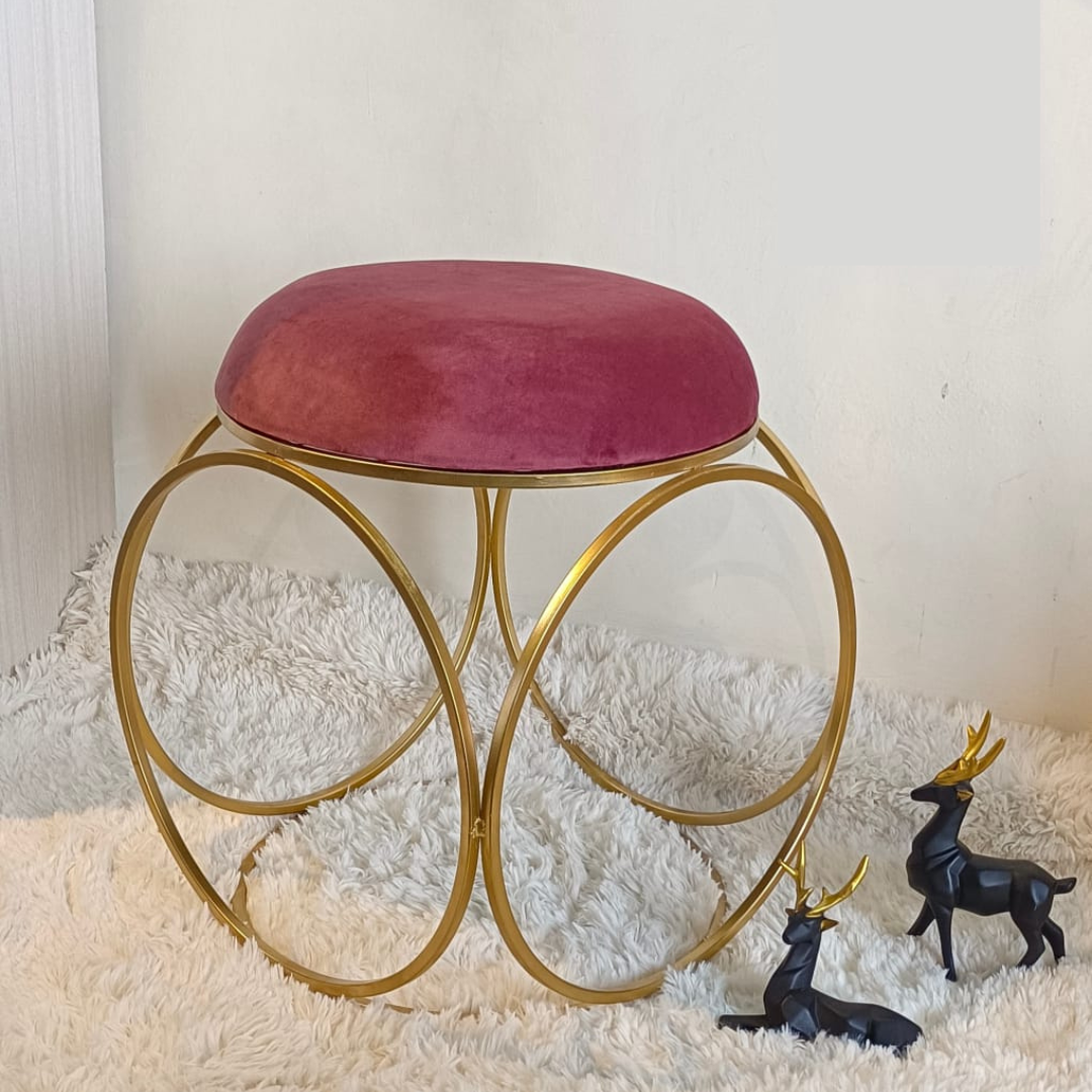 round design gold metal stool with puffy top in purple color placed on soft rug