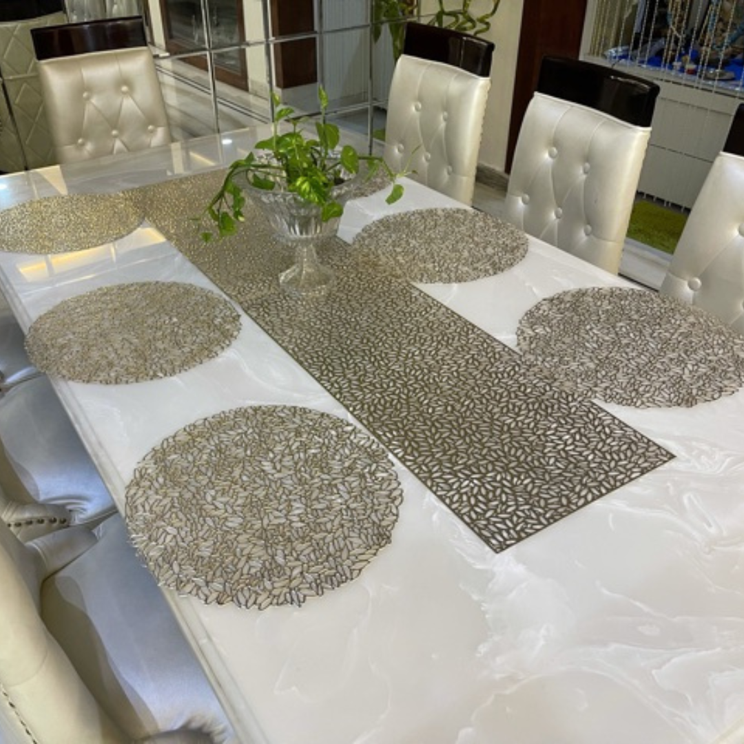metallic look round placemats in gold color with long runner placed on white marble table accessorized with glass pot