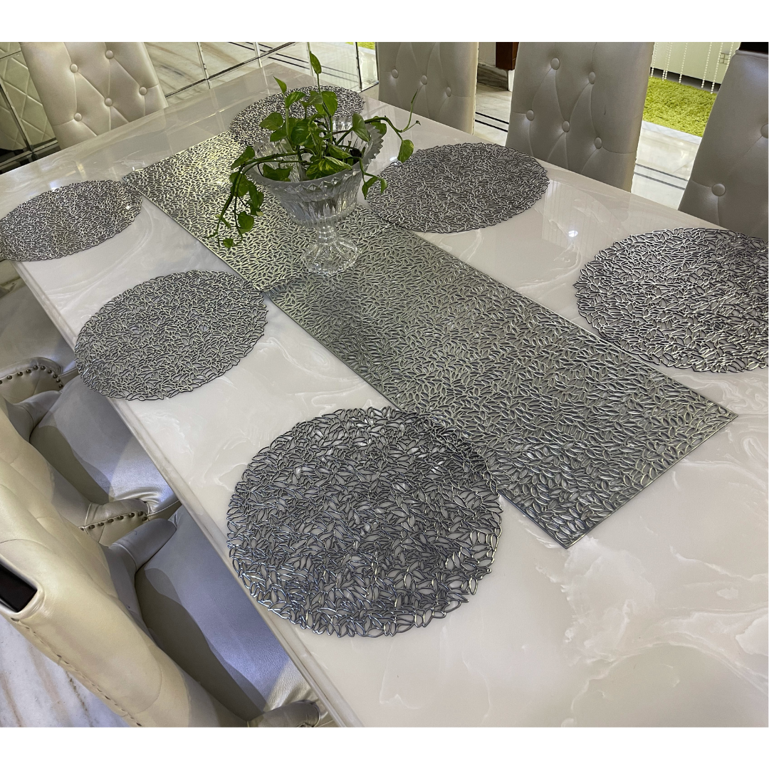 metallic look round placemats in silver color with long runner placed on white marble table accessorized with glass pot