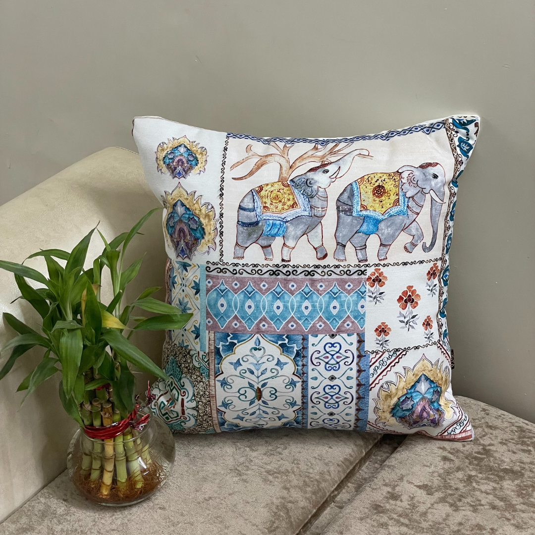 elephant printed cushion cover in blue color of 100% cotton fabric with madhubani print lies in the corner of sofa with a plant 