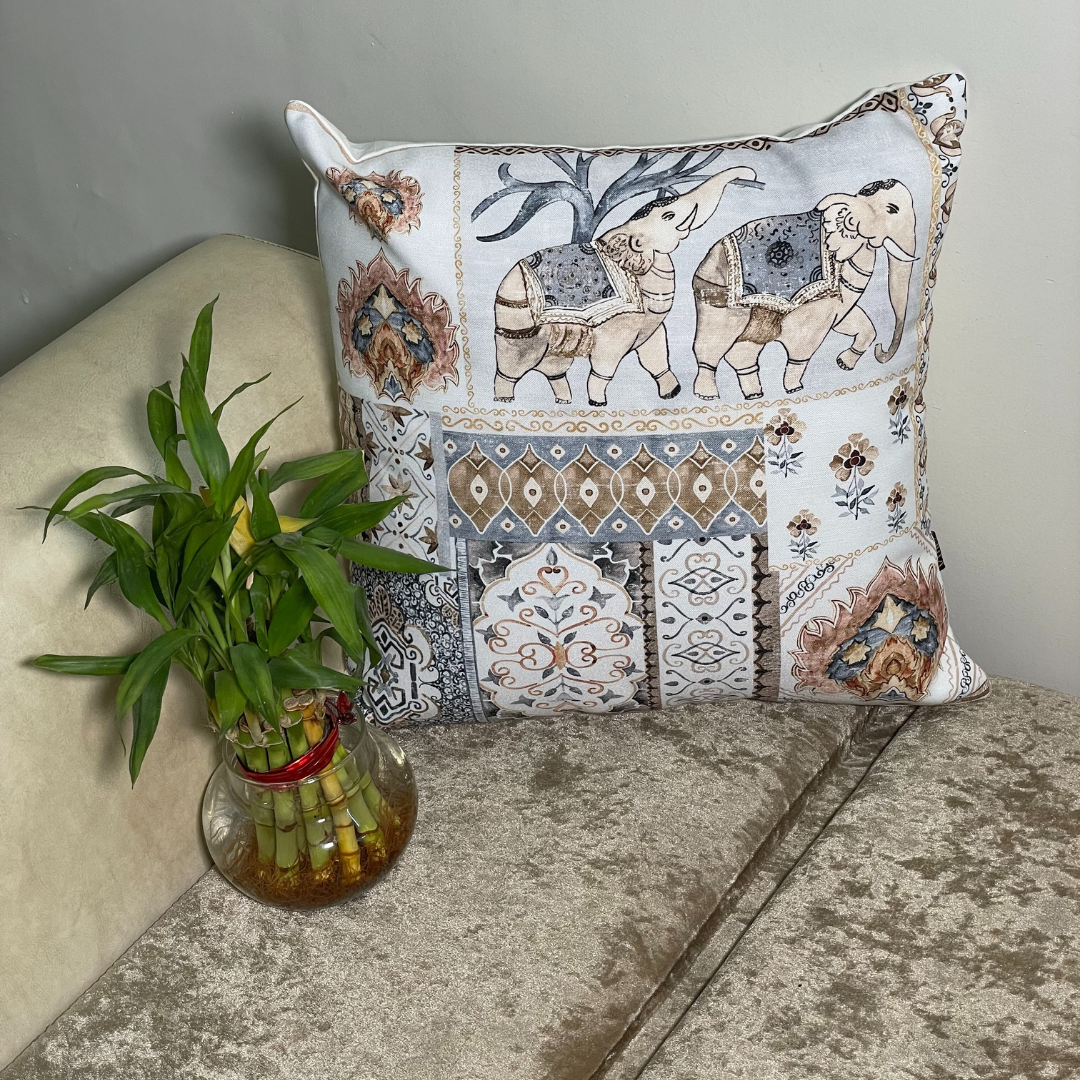elephant printed cushion cover in brown color of 100% cotton fabric with madhubani print lies in the corner of sofa with a plant 
