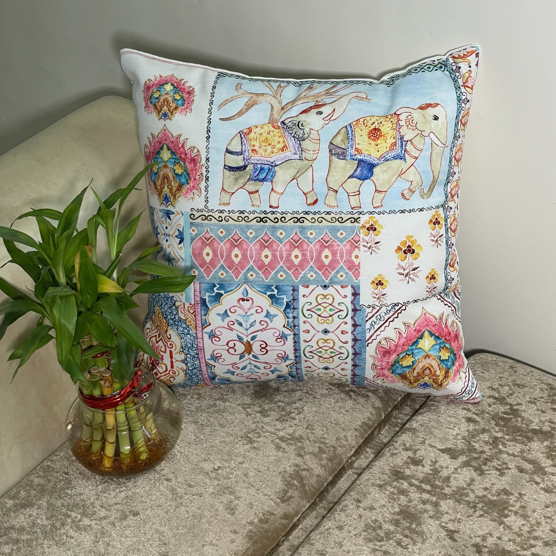 elephant printed cushion cover in pink color of 100% cotton fabric with madhubani print lies in the corner of sofa with a plant 