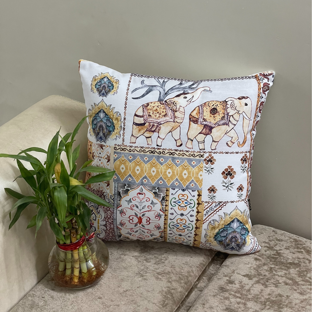 elephant printed cushion cover in yellow color of 100% cotton fabric with madhubani print lies in the corner of sofa with a plant 