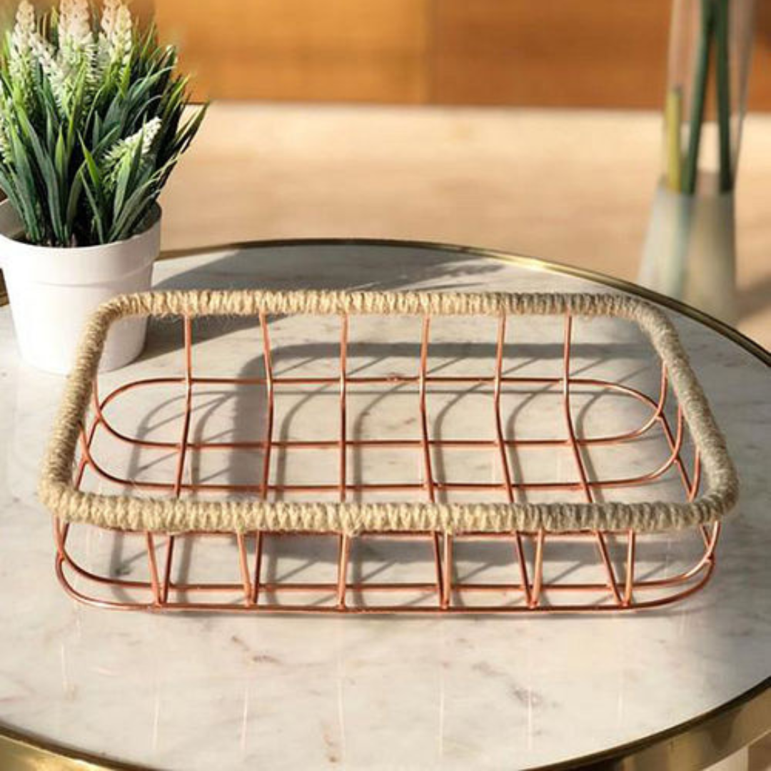 rose gold colored iron wired basket placed on marble round table near planter
