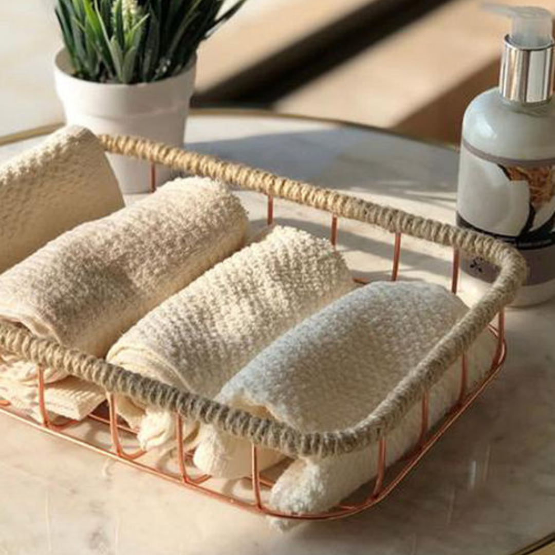 jute and iron wired basket placed on a marble table with four hand towels