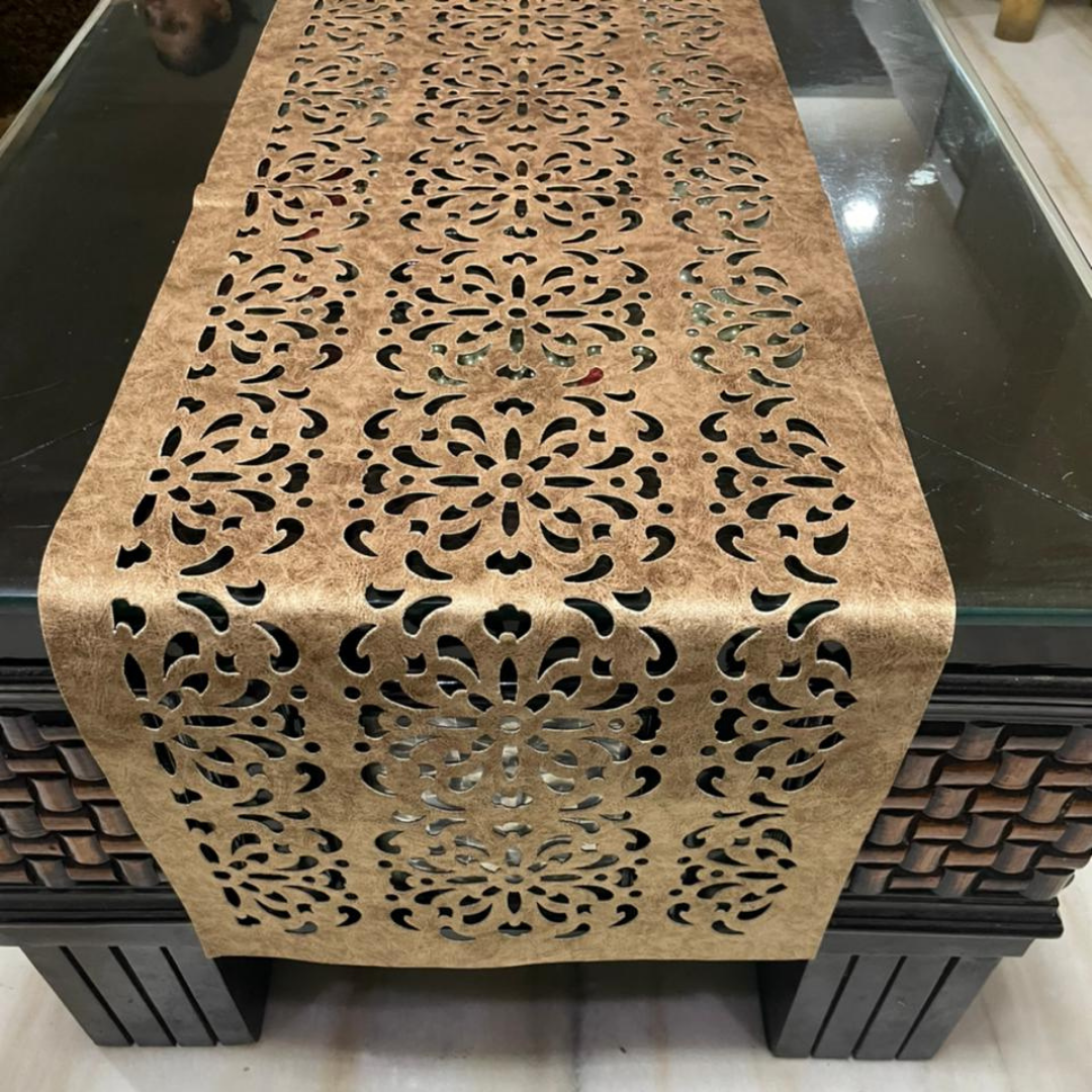 velvet table runner with floral laser cut design in brown color is placed on the black glass table front-view