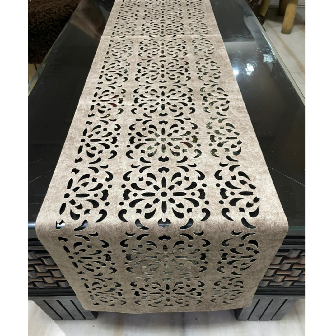 velvet table runner with floral laser cut design in silver color is placed on the black glass table front-view