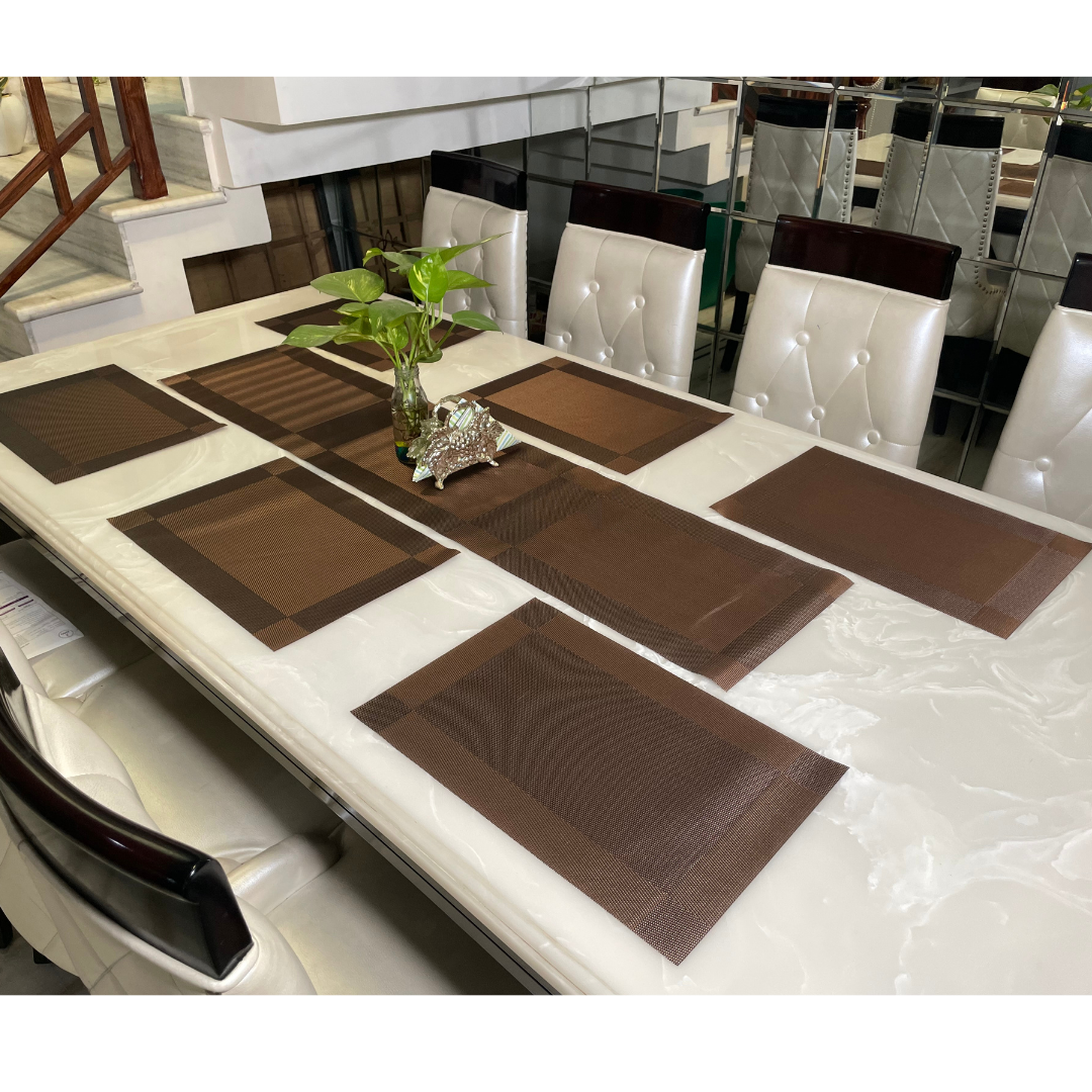 six placemats with one table runner in coffee color on white six seater dining table accessorized with vase and napkin holder