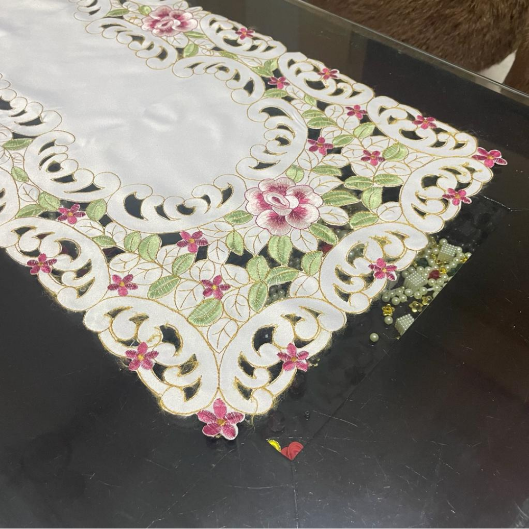 Tissue fabric embroidered with magenta flowers laser cut design placed on table zoom view