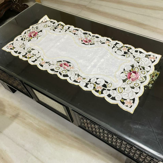 tissue fabric table runner with pink flower and green leaf embroidery placed on glass table 