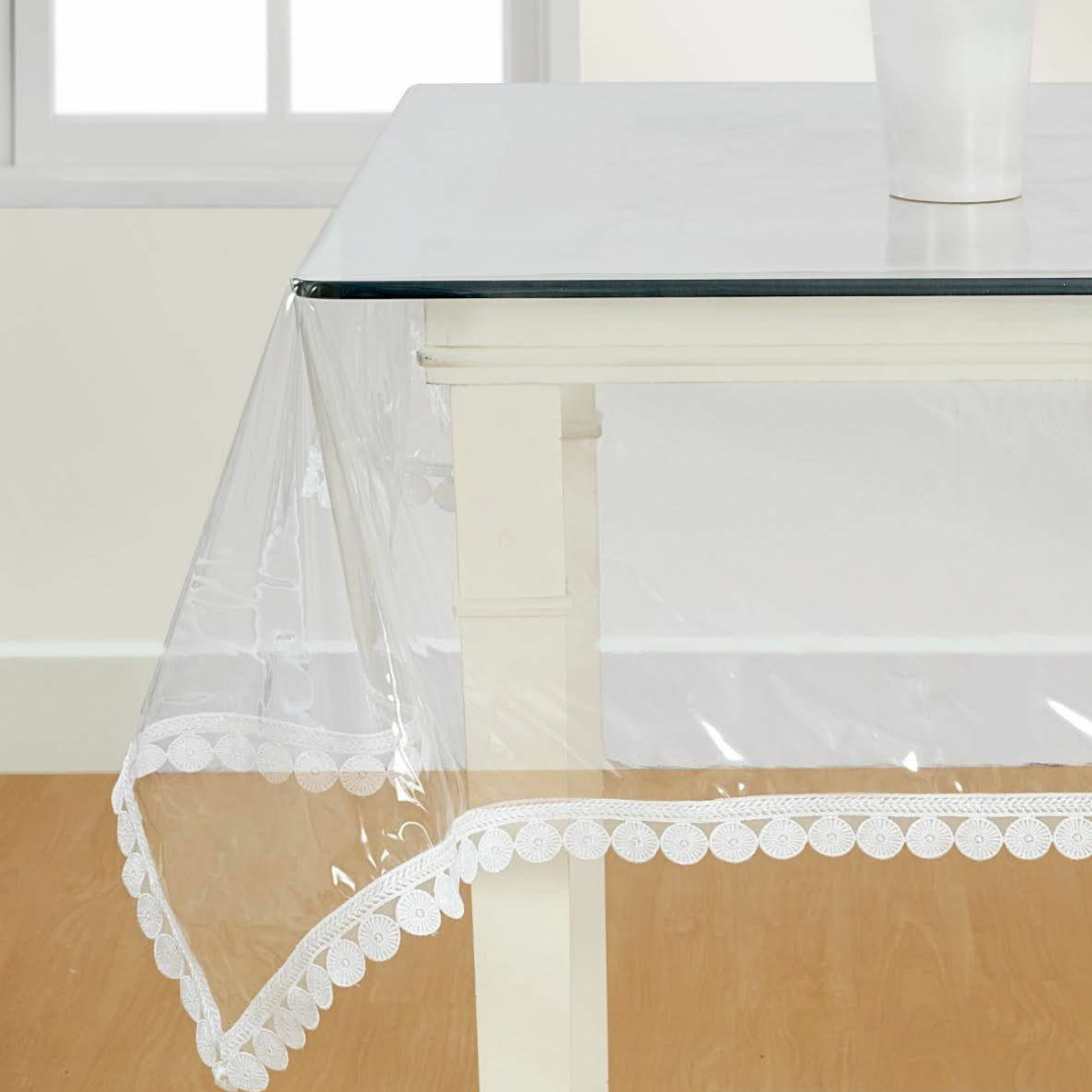 transparent table cover decorated with white color designer lace placed on glass table