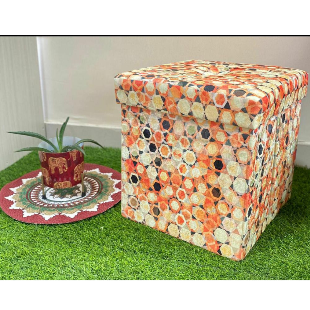 abstract printed orange color stool with storage placed on grass floor near small elephant printed pot