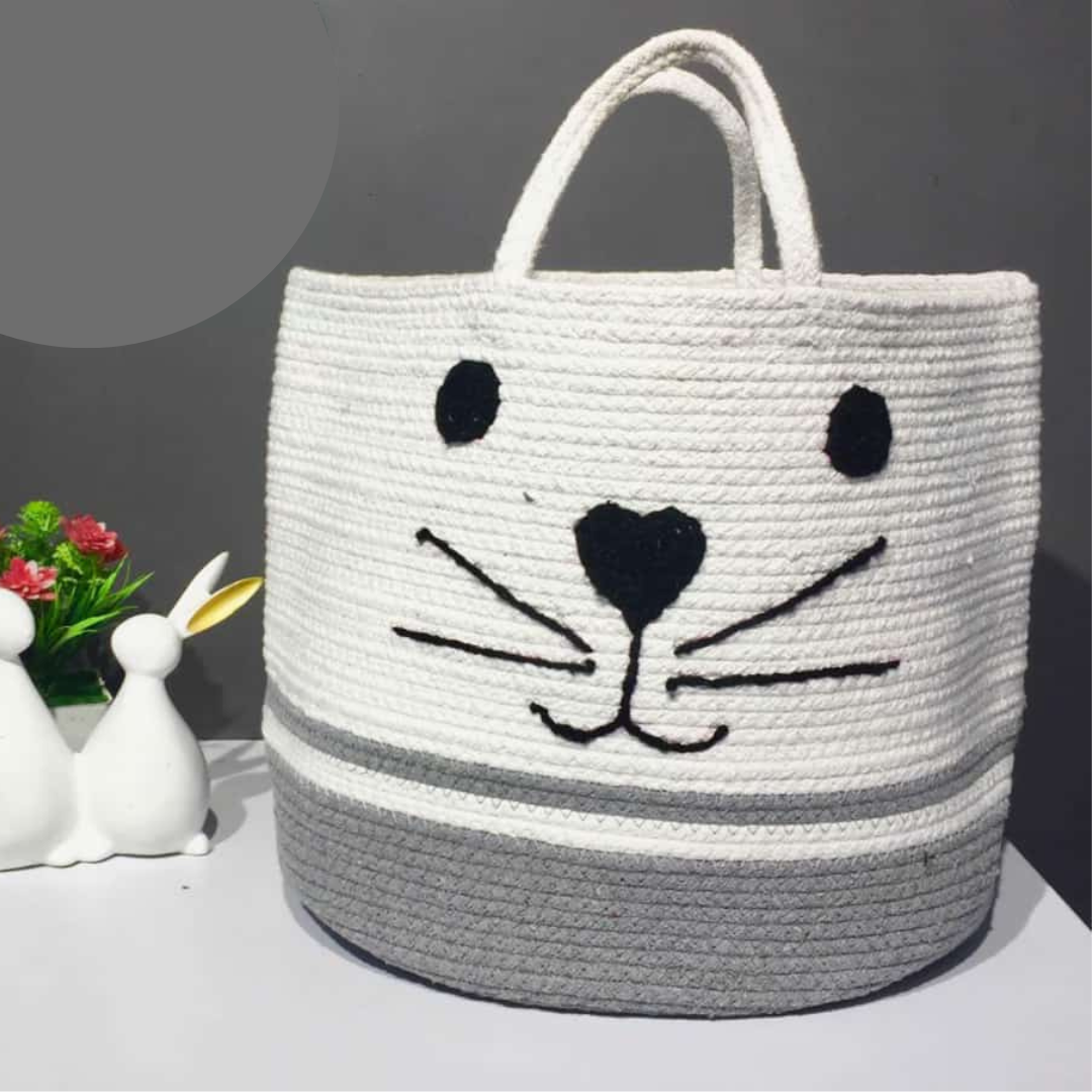 cotton rop basket in white and grey color with handles placed on table near rabbit decor piece and faux plant
