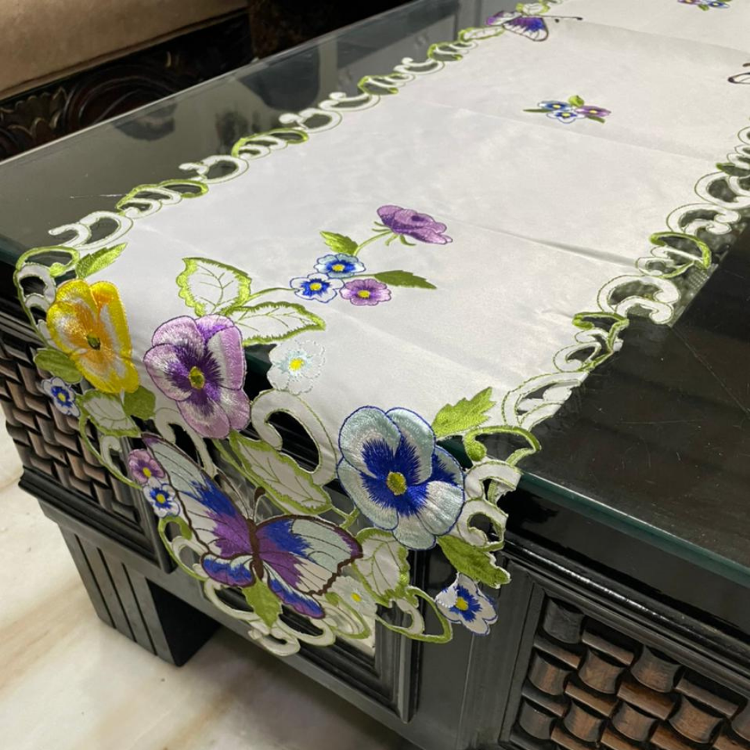 tissue fabric table runner embroidered with purple blue flowers and green leaves on border shaped cut design placed on the dining table side view