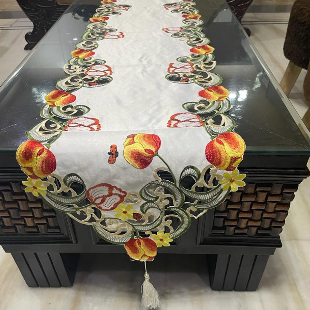 tissue fabric table runner embroidered with red flowers and green leaves on border shaped cut design placed on the dining table front view