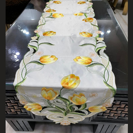 tissue fabric table runner embroidered with yellow flowers and green leaves on border shaped cut design placed on the dining table front view